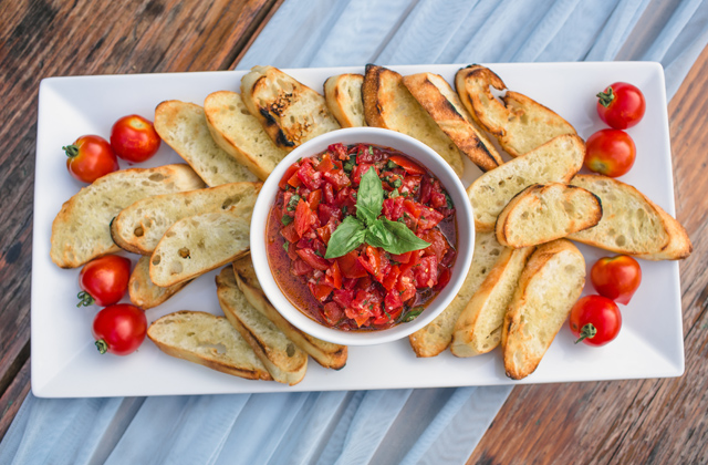 bruschetta and sliced toasted bread with cherry tomatoes on a serving platter
